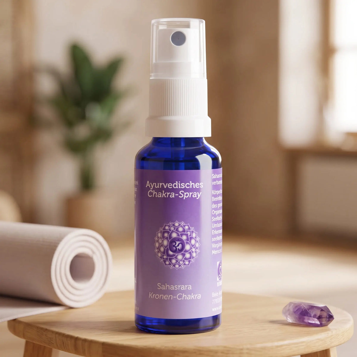 Ayurvedisches Chakra-Spray Sahasrara (Kronen-Chakra): 30-ml-Sprühflasche auf einem Holzhocker neben einer gerollten Yogamatte, daneben Amethyst