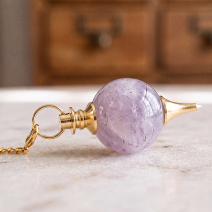 Nahaufnahme der violetten Amethystkugel mit gestufter Messingkappe und Messingspitze, liegend auf Marmor