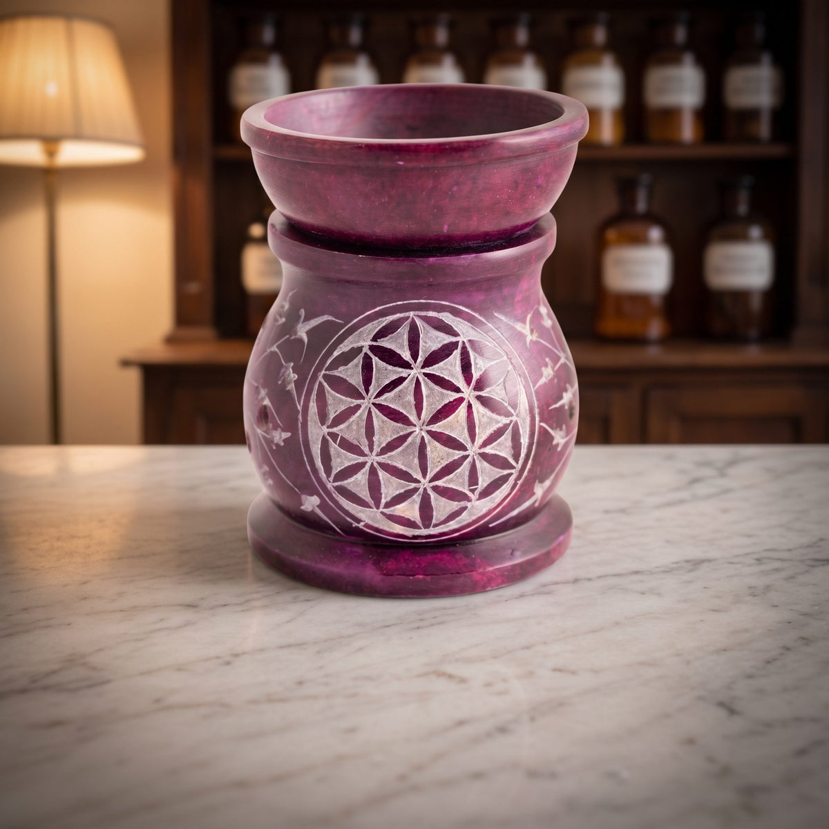 Aromalampe Blume des Lebens aus violettem Speckstein mit Schale auf der Marmortheke einer Apotheke am Abend