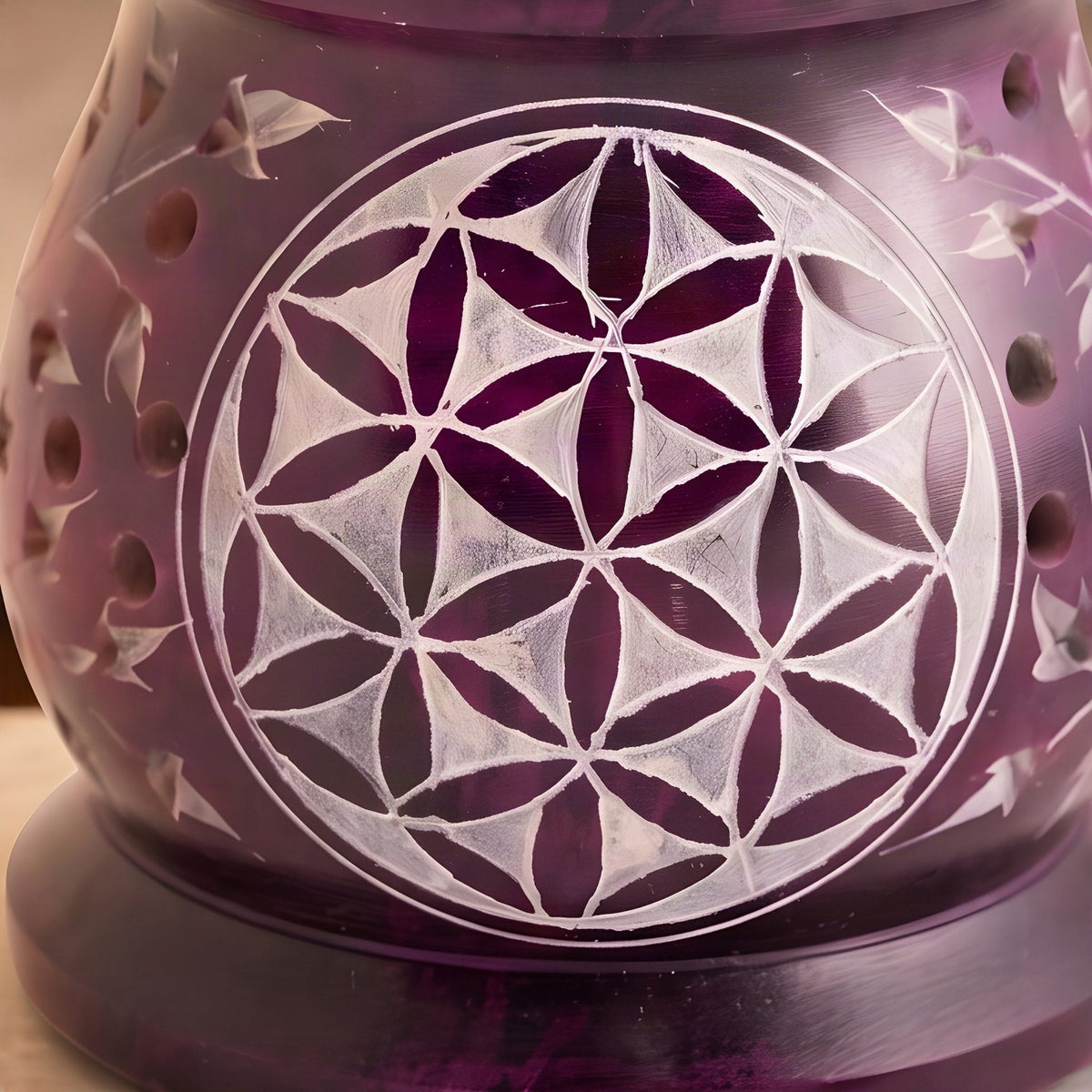 Nahaufnahme der Blume des Lebens im hellen Kreis und der runden Löcher in der violetten Specksteinwand
