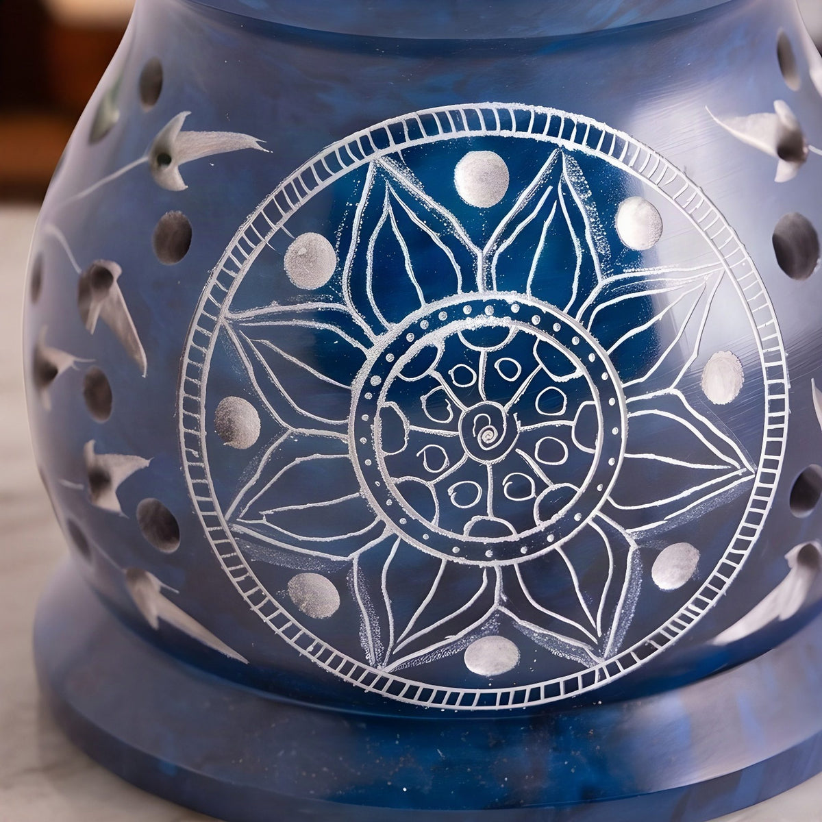 Nahaufnahme des Mandalas aus Blütenblättern im hellen Kreis und der runden Löcher in der blauen Specksteinwand