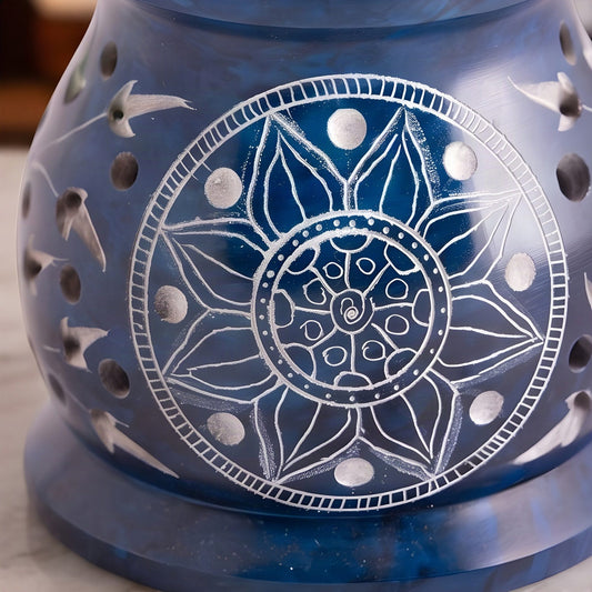 Nahaufnahme des Mandalas aus Blütenblättern im hellen Kreis und der runden Löcher in der blauen Specksteinwand