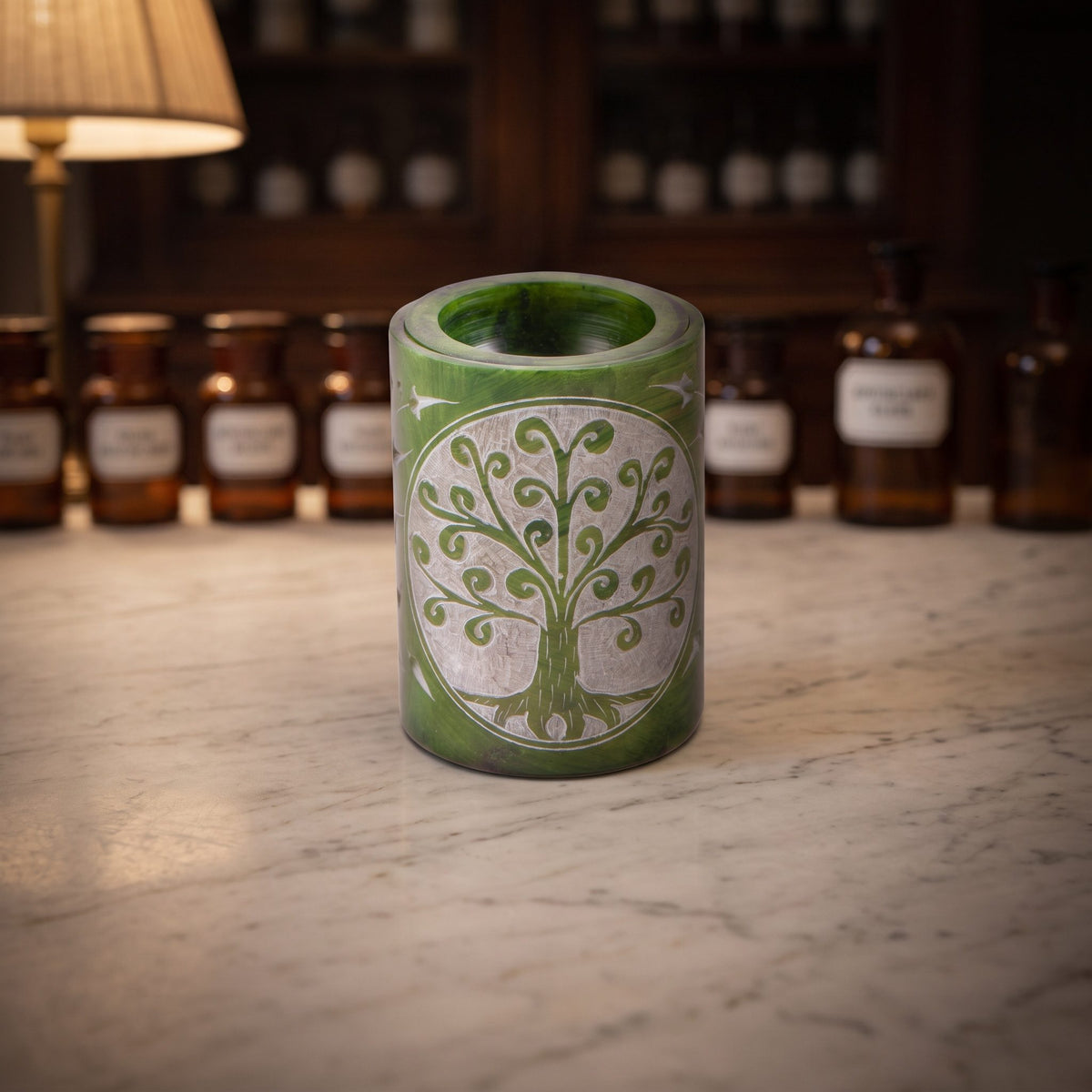 Aromalampe Zylinder Yggdrasil aus grünem Speckstein auf der Marmortheke einer Apotheke am Abend