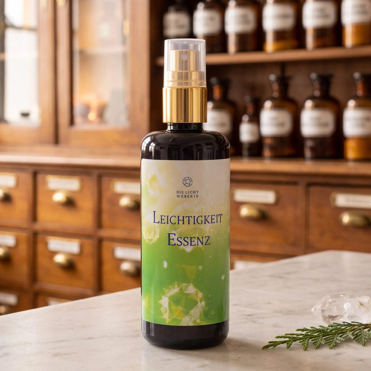 Aura Spray Leichtigkeit der Lichtweberin: Flasche aus Violettglas mit goldener Pumpe auf einer Marmortheke vor einem Apothekerschrank