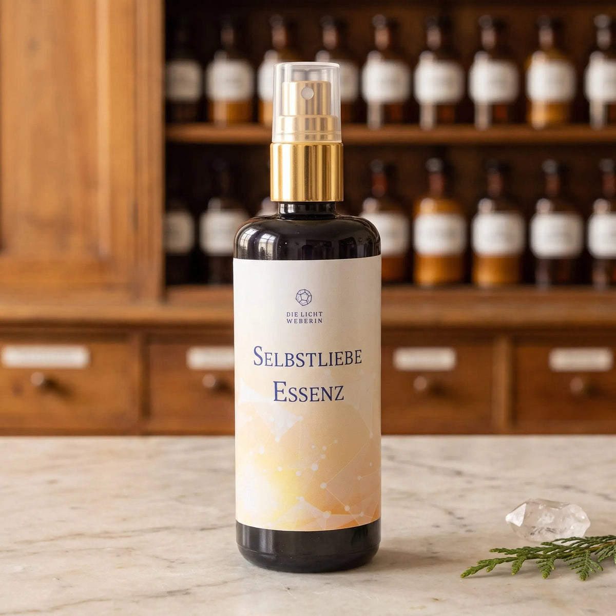 Aura Spray Selbstliebe der Lichtweberin: Flasche aus Violettglas mit goldener Pumpe auf einer Marmortheke vor einem Apothekerschrank