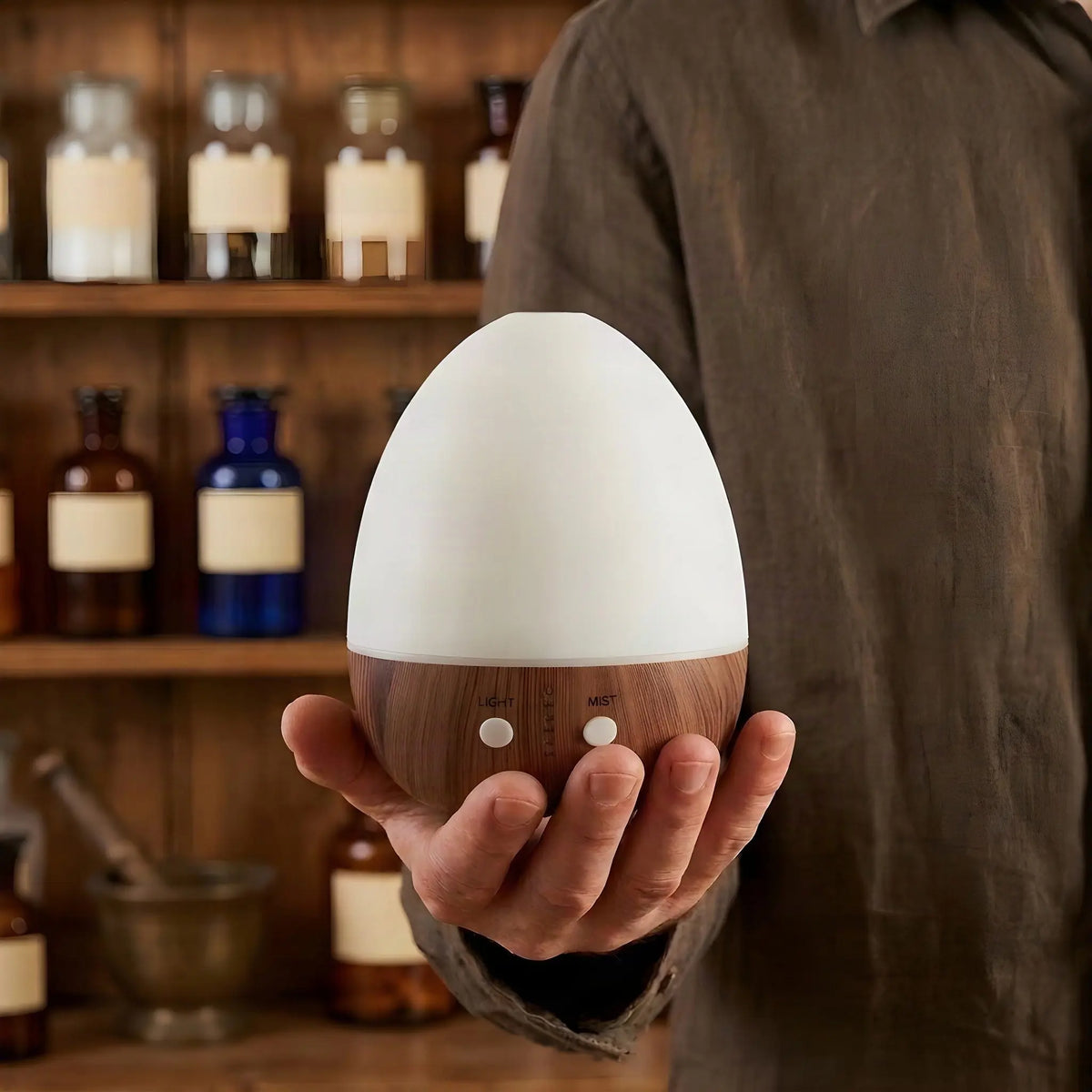 Hand hält den 15,8 cm hohen Aroma Diffuser Oval Weiß vor einem Apothekerregal