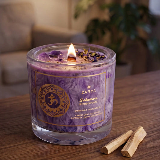 Chakra-Kerze Kronenchakra Sahasrara mit Amethyst, Duft Sandelholz und Mandel: brennende Kerze mit kleiner Flamme am Abend auf einer dunklen Holzplatte im Wohnzimmer, daneben zwei Stücke Sandelholz – Spirit of Gaia
