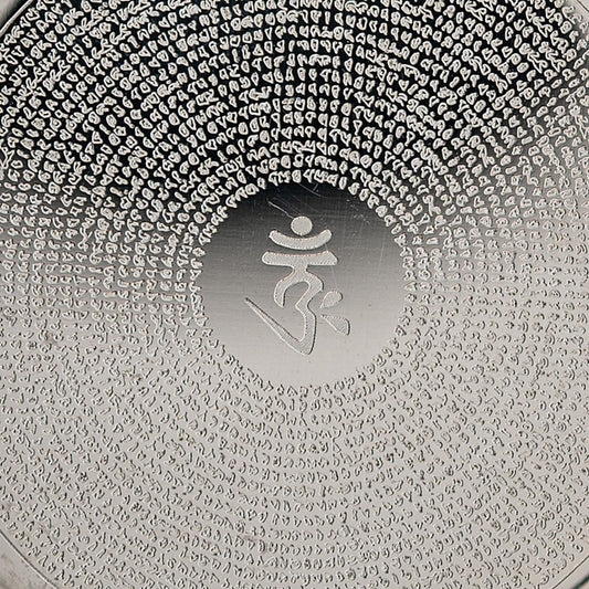 Nahaufnahme des OM im glatten Mittelfeld und der Mantra-Gravur in feinen Kreisen auf silberfarbenem Edelstahl