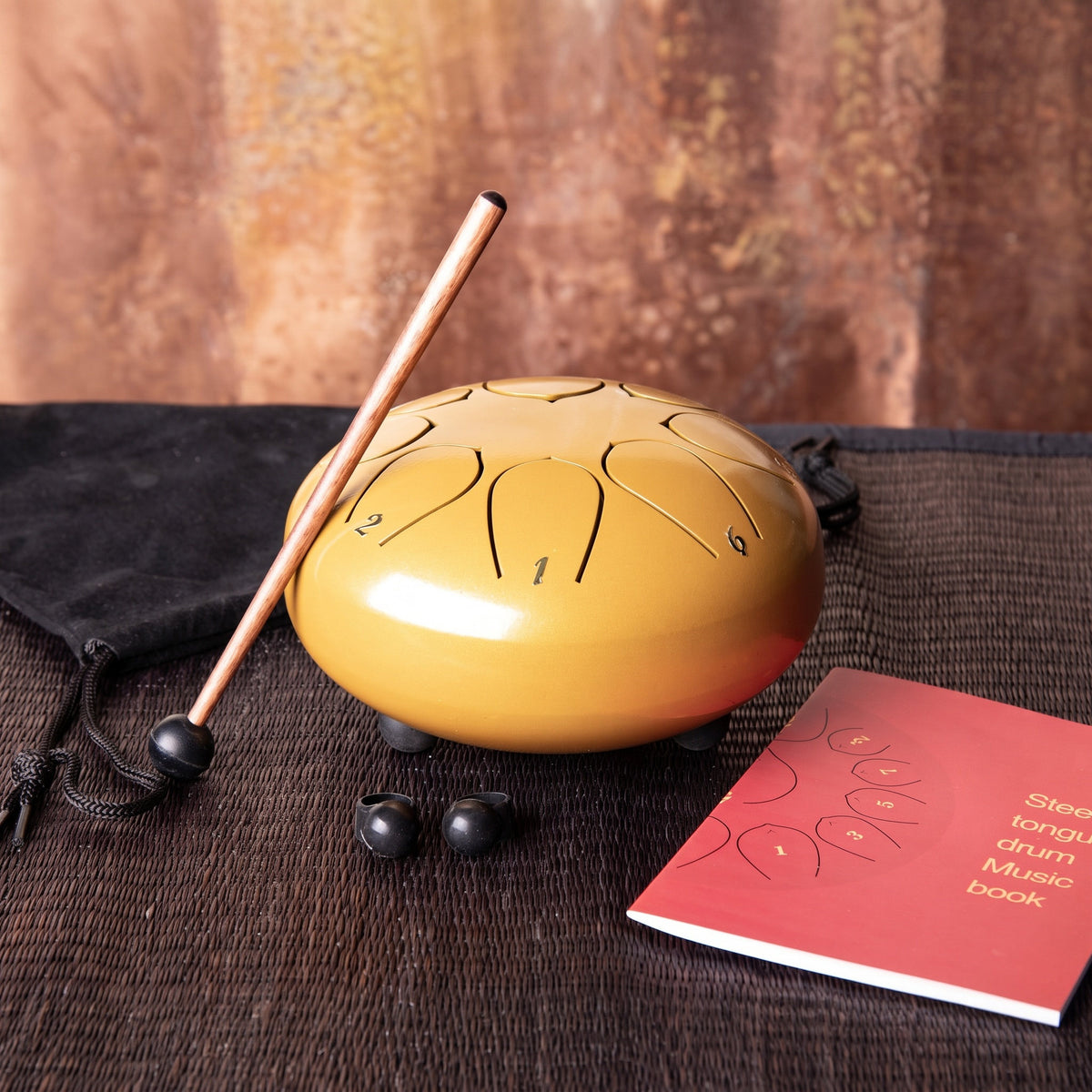 Die mittlere goldene Steeldrum mit Klangstab, Fingerkuppen, Liederbuch und Tasche