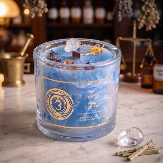 Chakra-Kerze Stirnchakra Ajna mit Bergkristall, Duft Zitronengras und Mandel: Kerze im Glas auf der Marmortheke einer alten Apotheke am Abend, daneben ein Bergkristall und getrocknetes Zitronengras – Spirit of Gaia
