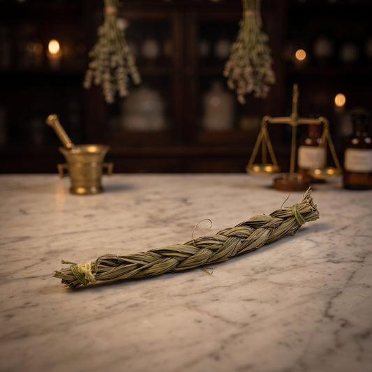 Sweetgrass-Zopf (Süßgras): handgeflochtener Zopf mit grünen Fadenwicklungen an beiden Enden auf der Marmortheke einer alten Apotheke am Abend – Spirit of Gaia