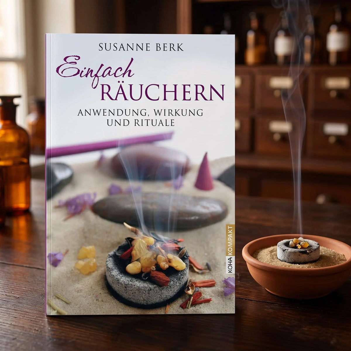 Das Buch Einfach Räuchern neben einer Terracottaschale mit Räucherkohle und Harz in der abendlichen Apotheke