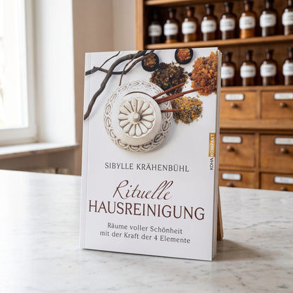 Buch Rituelle Hausreinigung von Sibylle Krähenbühl steht auf der Marmortheke einer hellen Apotheke