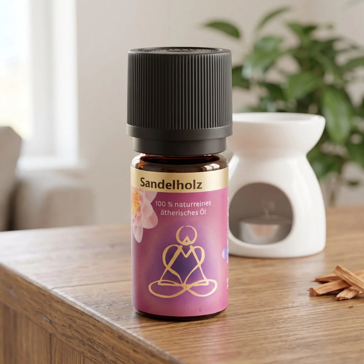 Ätherisches Öl Sandelholz: Fläschchen auf einem Holz-Sideboard im Wohnzimmer, im Hintergrund eine weiße Duftlampe, daneben Sandelholzspäne