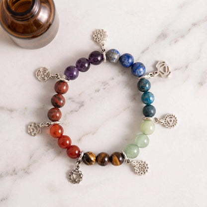Chakra-Armband von Berk flach auf heller Marmortheke: einundzwanzig Steinkugeln in sieben Farben mit sieben silberfarbenen Chakra-Anhängern