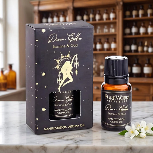 Aromaöl Divine Goddess (Jasmin & Oud) von Pure Works: Fläschchen und schwarze Schachtel mit Goldprägung auf Marmortheke vor Apothekerschrank, daneben weiße Jasminblüten – Spirit of Gaia