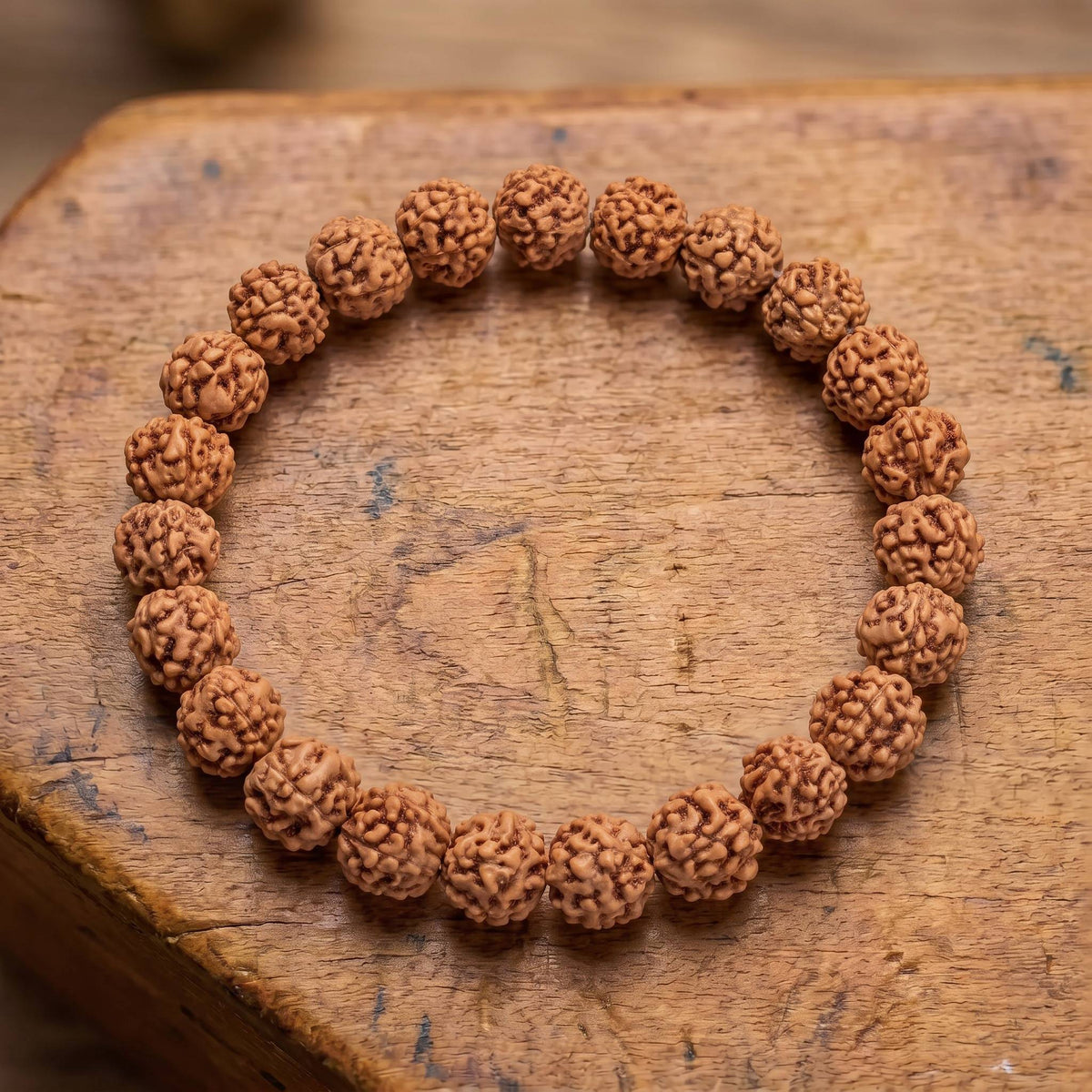 Draufsicht auf das Rudraksha Armband auf altem Holz: zerfurchte Rudraksha-Samen in einer Reihe