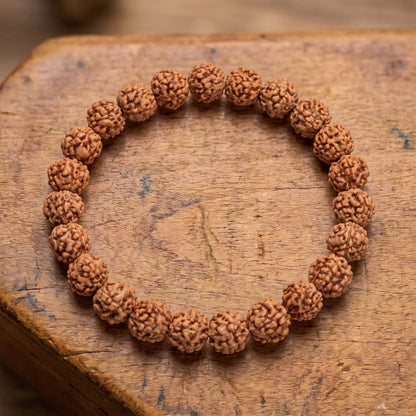 Draufsicht auf das Rudraksha Armband auf altem Holz: zerfurchte Rudraksha-Samen in einer Reihe