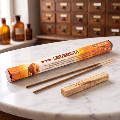 GR Palo Santo Räucherstäbchen: Sechseck-Packung auf einer Marmortheke vor einem Apothekerschrank, daneben zwei lose Räucherstäbchen – Spirit of Gaia