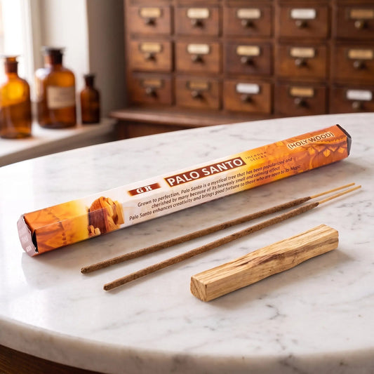 GR Palo Santo Räucherstäbchen: Sechseck-Packung auf einer Marmortheke vor einem Apothekerschrank, daneben zwei lose Räucherstäbchen – Spirit of Gaia