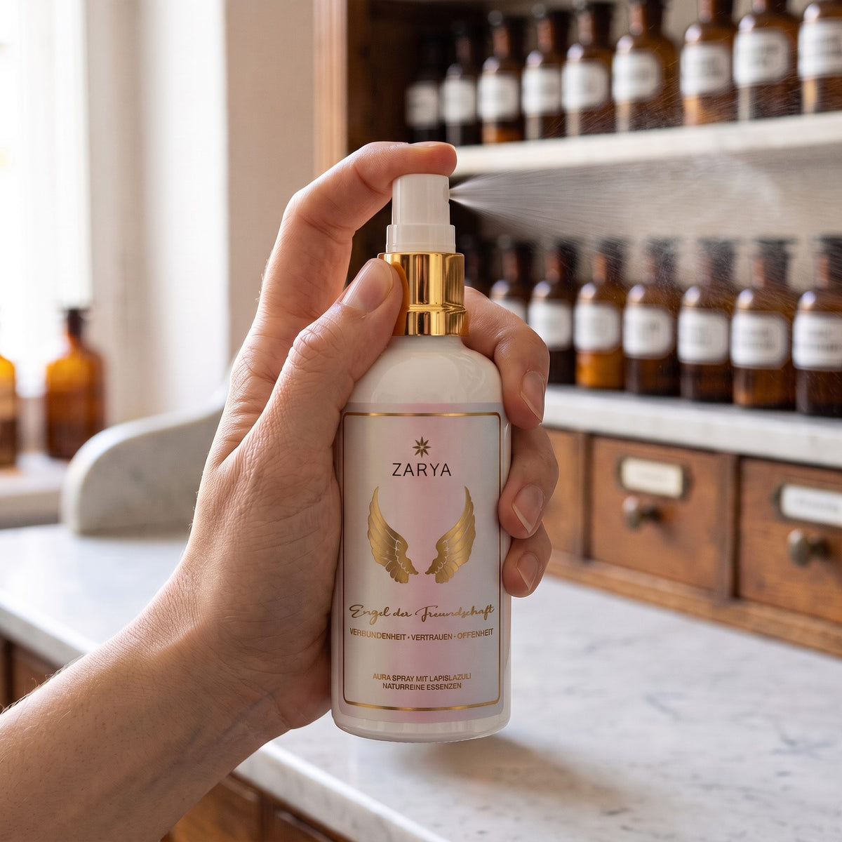 Eine Hand sprüht das Aura Spray Engel der Freundschaft fein in den Raum