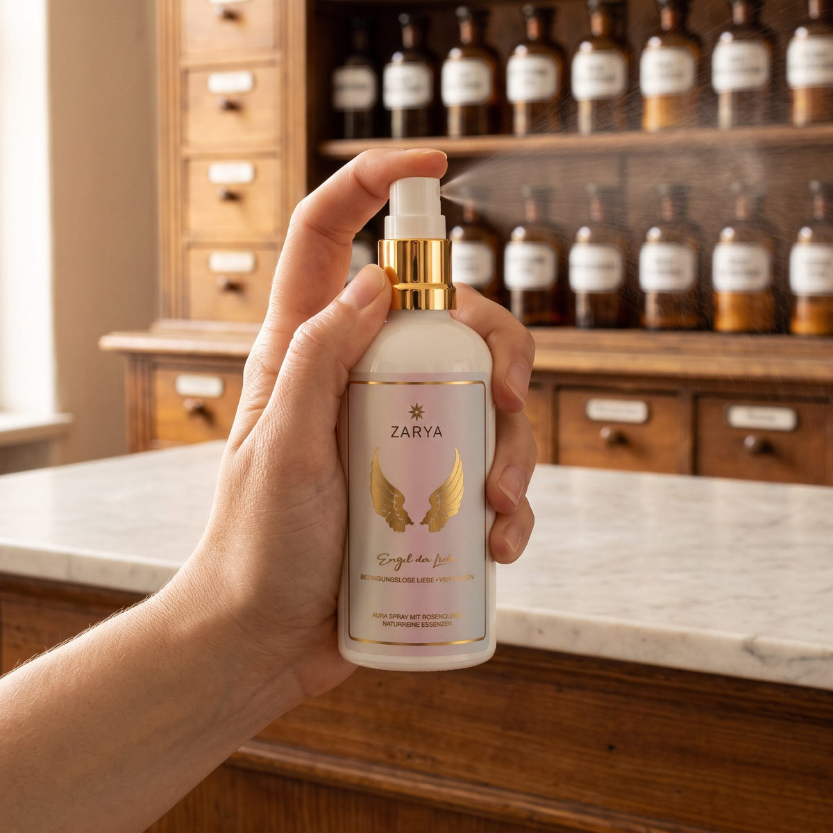 Eine Hand sprüht das Aura Spray Engel der Liebe fein in den Raum