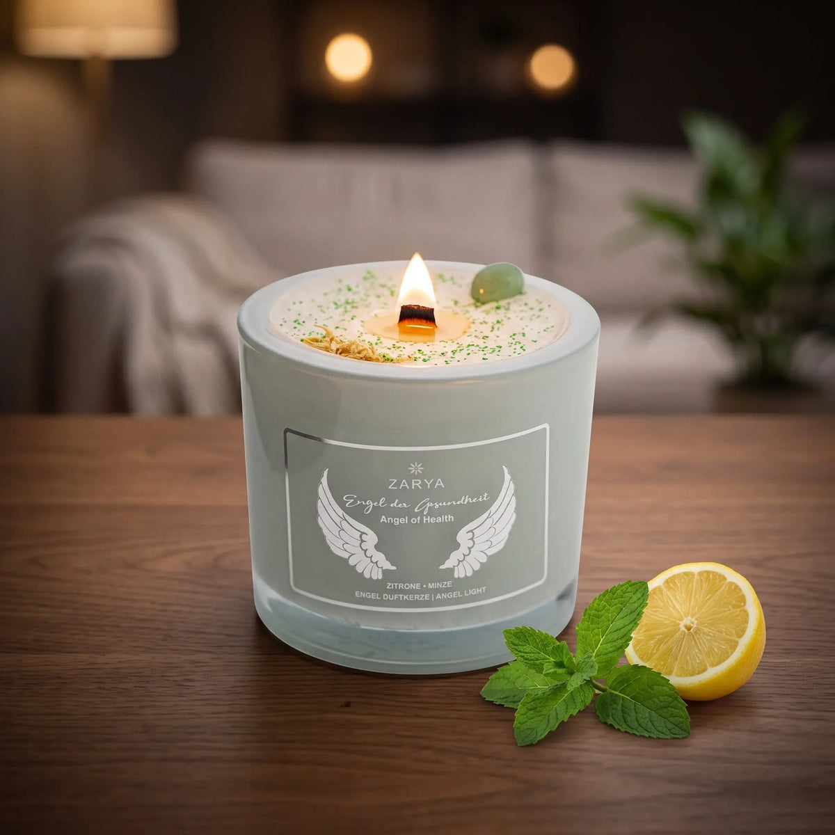 Engelkerze Engel der Gesundheit brennt am Abend auf einem dunklen Holztisch im Wohnzimmer, daneben frische Minze und eine halbe Zitrone – Spirit of Gaia