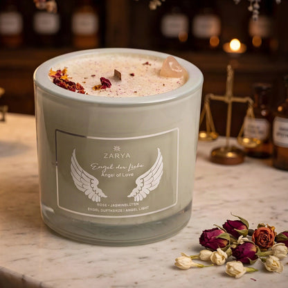 Engelkerze Engel der Liebe von Zarya: salbeigrünes Glas mit weißem Aufdruck auf der Marmortheke einer alten Apotheke am Abend, daneben getrocknete Rosenknospen und Jasminblüten – Spirit of Gaia