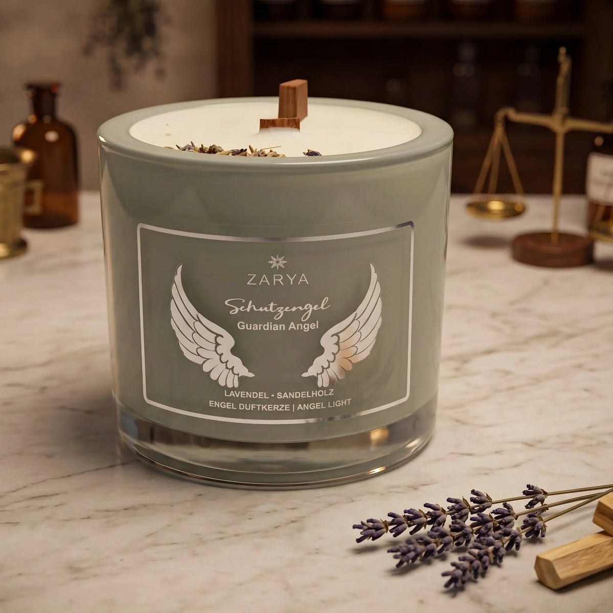 Engelkerze Schutzengel von Zarya: salbeigrünes Glas mit weißem Aufdruck auf der Marmortheke einer alten Apotheke am Abend, daneben getrockneter Lavendel und ein Stück Sandelholz – Spirit of Gaia