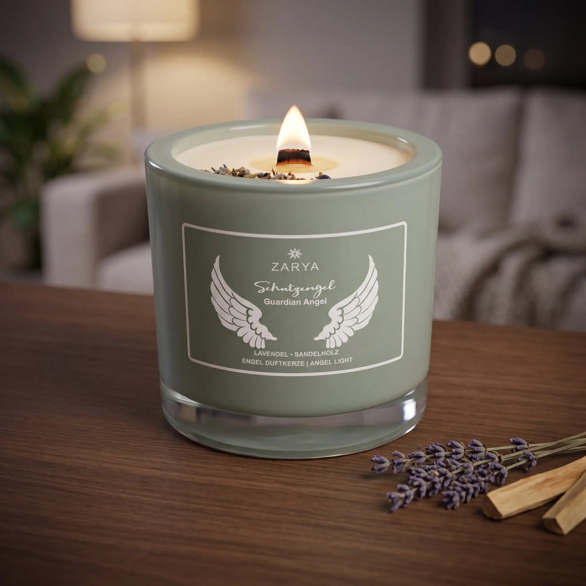 Engelkerze Schutzengel brennt am Abend auf einem dunklen Holztisch im Wohnzimmer, daneben getrockneter Lavendel und Stücke Sandelholz – Spirit of Gaia