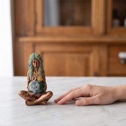 Die 14,5 cm hohe Erdmuttergöttin neben einer Hand auf der Theke