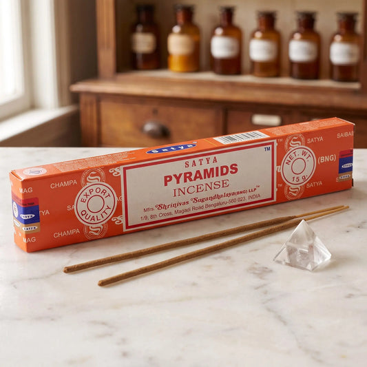 Satya Pyramids Räucherstäbchen: 15-g-Packung auf einer Marmortheke vor einem Apothekerschrank, daneben zwei lose Räucherstäbchen – Spirit of Gaia