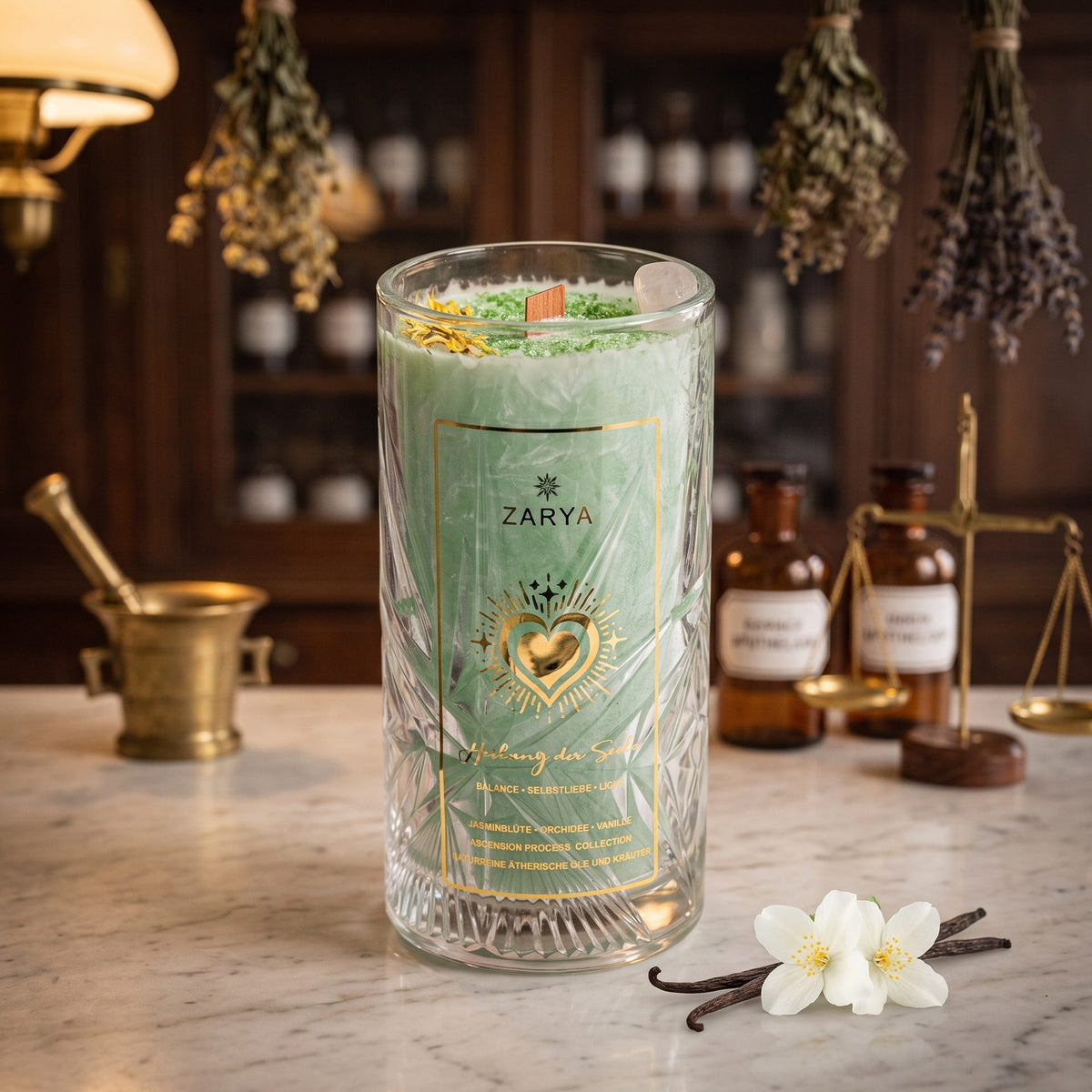 Zarya Kerze Heilung der Seele im hohen Glas mit Schliffmuster und goldenem Etikett auf der Marmortheke einer Apotheke am Abend, daneben Jasminblüten und Vanilleschoten