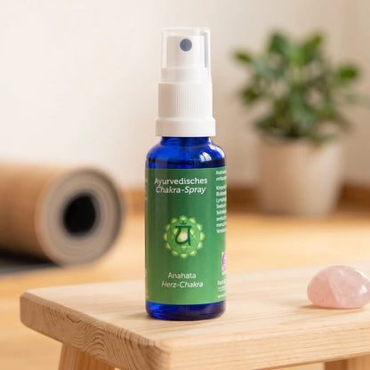 Ayurvedisches Chakra-Spray Anahata (Herz-Chakra): 30-ml-Sprühflasche auf einem Holzhocker neben einer gerollten Yogamatte, daneben Rosenquarz