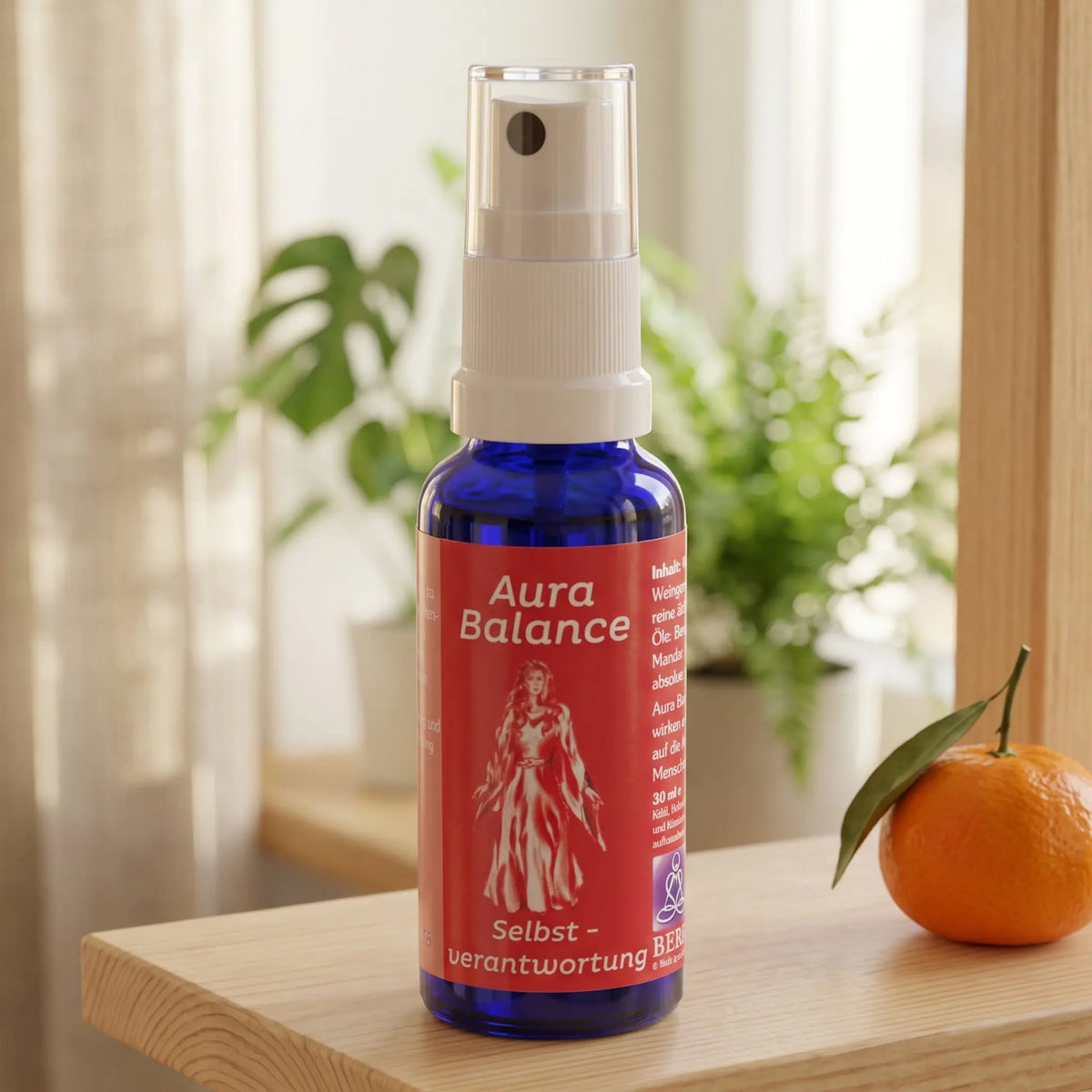 Energiespray Selbstverantwortung (Aura Balance): Sprühflasche auf einem hellen Holzregal am Fenster mit Leinenvorhang, daneben eine Mandarine