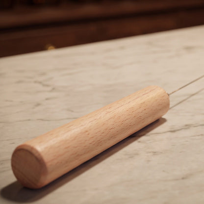 Tensor aus Buchenholz mit Federstahlrute, ca. 41,5 cm: Nahaufnahme des Buchenholzgriffs mit der Federstahlrute auf der Marmortheke – Spirit of Gaia