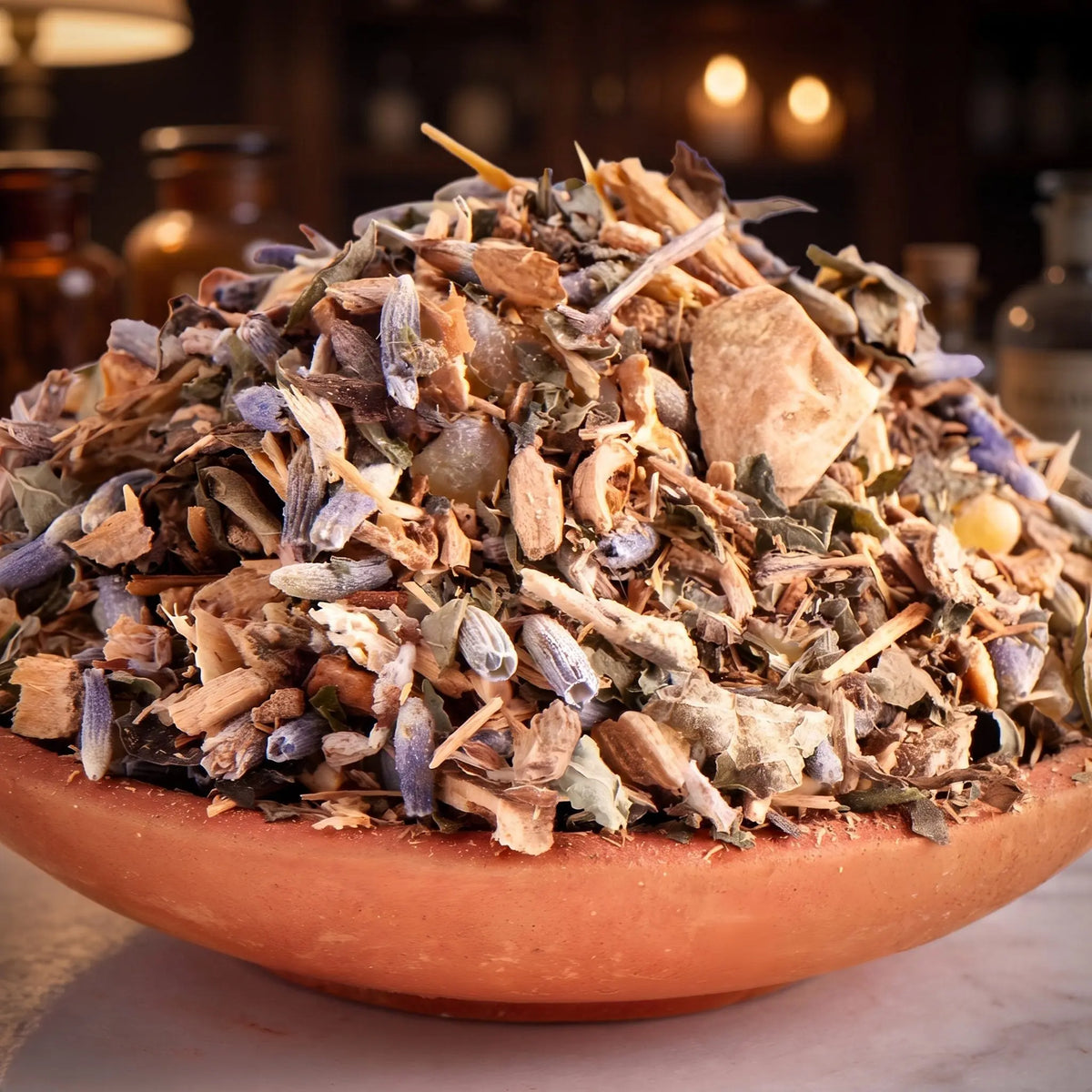 Hilfe bei Liebeskummer, Räuchermischung der Reihe Kraftvoll Räuchern von Berk, 60 ml im Bügelglas: Nahaufnahme der Terracottaschale mit Kräutern, Lavendel und hellen Wurzelstücken vor der warmen, unscharfen Abendapotheke – Spirit of Gaia