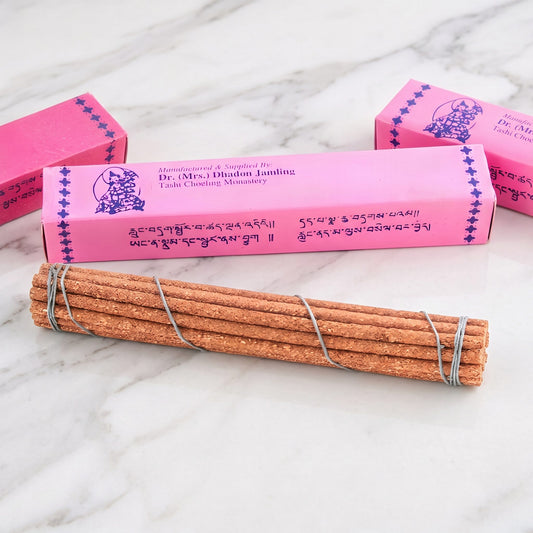 Nahaufnahme einer rosa Päckchen-Schachtel von Tara Healing Incense mit tibetischer Schrift, davor das Stäbchenbündel mit grauem Faden