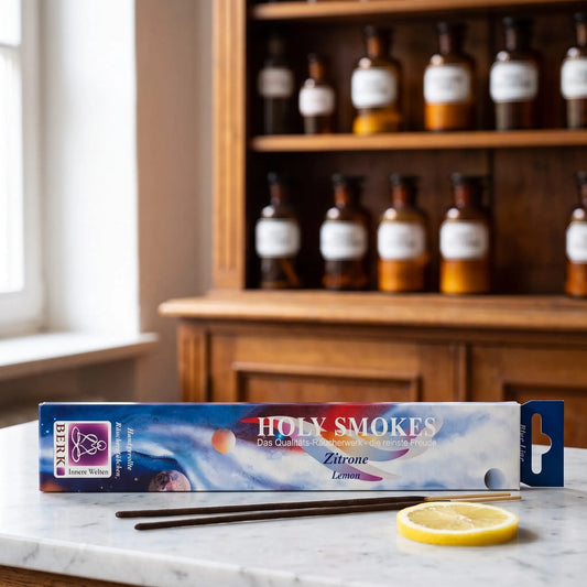 Zitrone Räucherstäbchen Holy Smokes Blue Line: Packung auf einer Marmortheke vor einem Apothekerschrank, davor zwei lose Räucherstäbchen und eine Zitronenscheibe – Spirit of Gaia