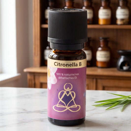 Ätherisches Öl Citronella: Fläschchen aus Braunglas auf Marmortheke vor Apothekerschrank, daneben Citronellagras – Spirit of Gaia