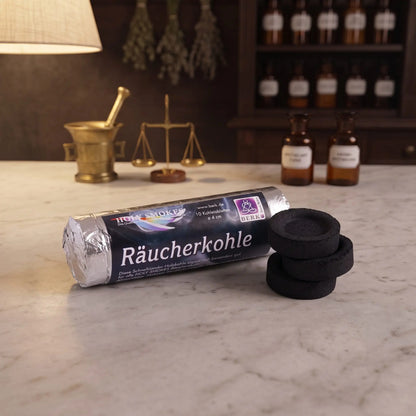 Kohletabletten Ø 4 cm von Berk: Rolle Räucherkohle der Reihe Holy Smokes mit drei Tabletten auf der Marmortheke einer Apotheke am Abend