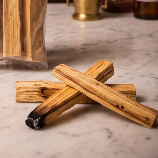 Palo Santo Holzstäbe, 5 Stück, von Berk: Nahaufnahme von drei Palo-Santo-Holzstäben auf der Marmortheke, Maserung und Holzfarbe vor der warmen, unscharfen Abendapotheke – Spirit of Gaia