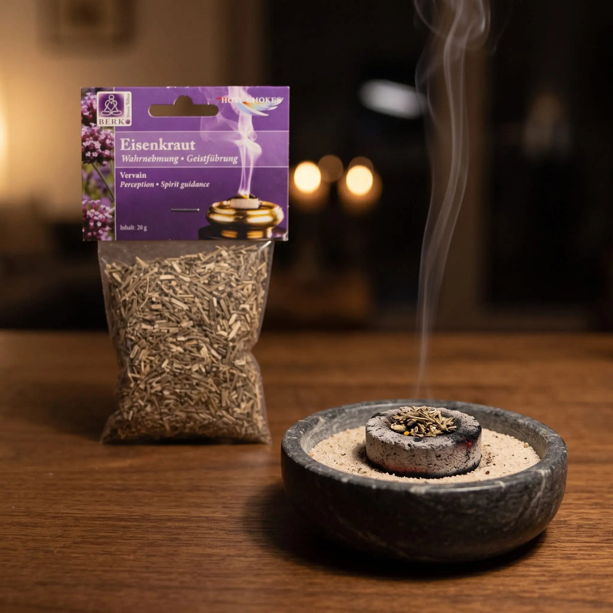 Eisenkraut, sortenreines Räucherwerk von Berk, 20 g: eine Prise Eisenkraut glimmt auf der Räucherkohle, dahinter die Tüte, feiner Rauch steigt auf einer dunklen Holzplatte am Abend auf – Spirit of Gaia