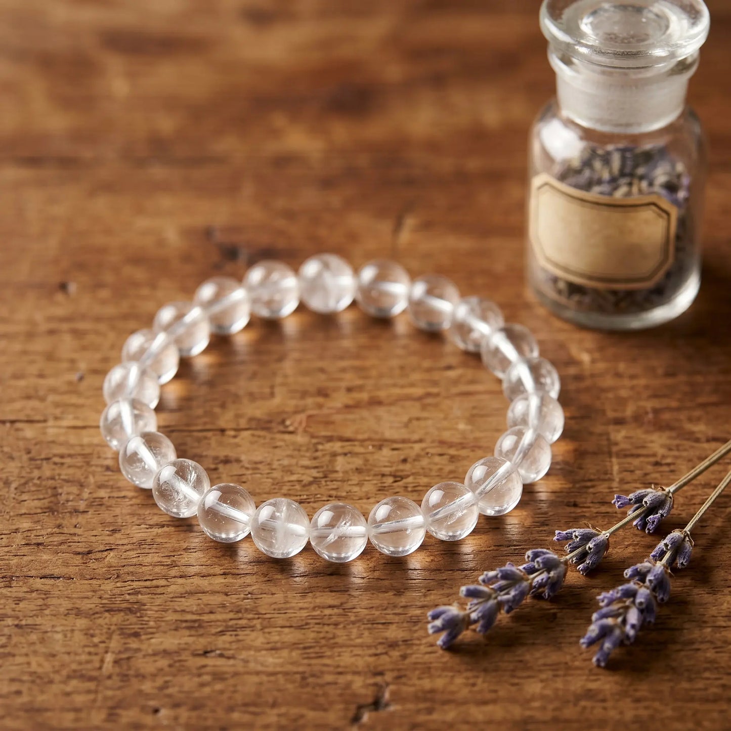 Bergkristall Kugelarmband auf warmem Holz mit getrocknetem Lavendel im Apotheker-Look