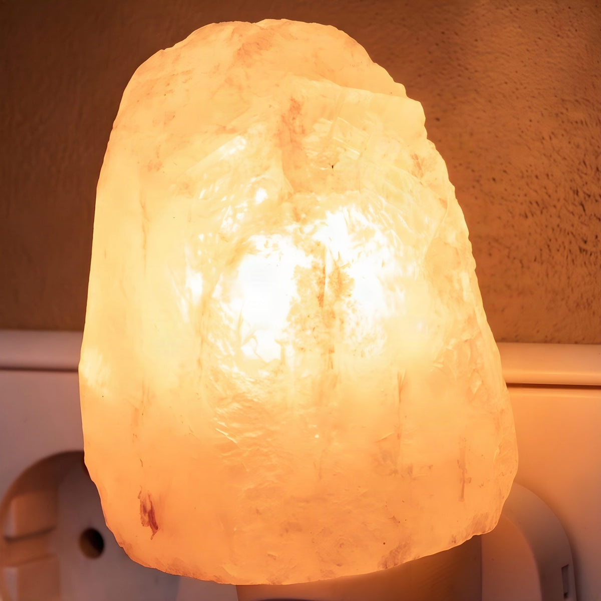 Nahaufnahme des leuchtenden Salzkristalls in Naturform mit rauen Flächen auf dem weißen Stecker