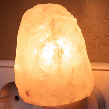 Nahaufnahme des leuchtenden Salzkristalls in Naturform mit rauen Flächen auf dem weißen Stecker