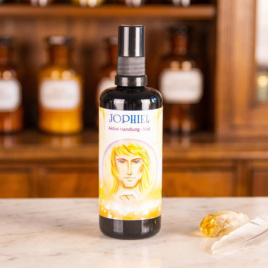 Seraphim Engel-Essenz Jophiel: Aura-Spray in dunkler Violettglasflasche auf Marmortheke vor Apothekerschrank, daneben ein Citrin und eine weiße Feder – Spirit of Gaia