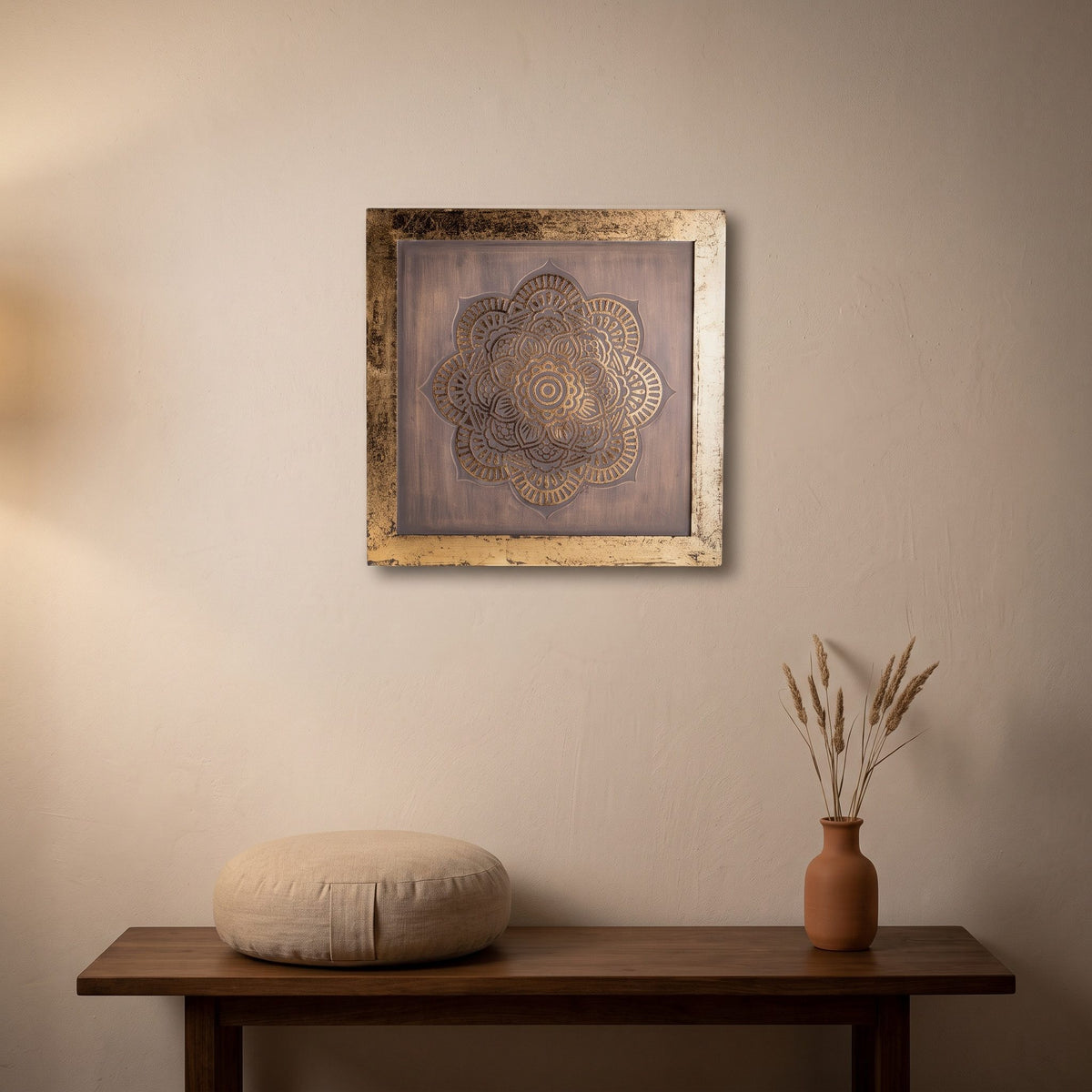Das Mandala-Wandbild mit goldenem Rahmen über einer Holzbank mit Meditationskissen und einer Vase mit Trockengräsern