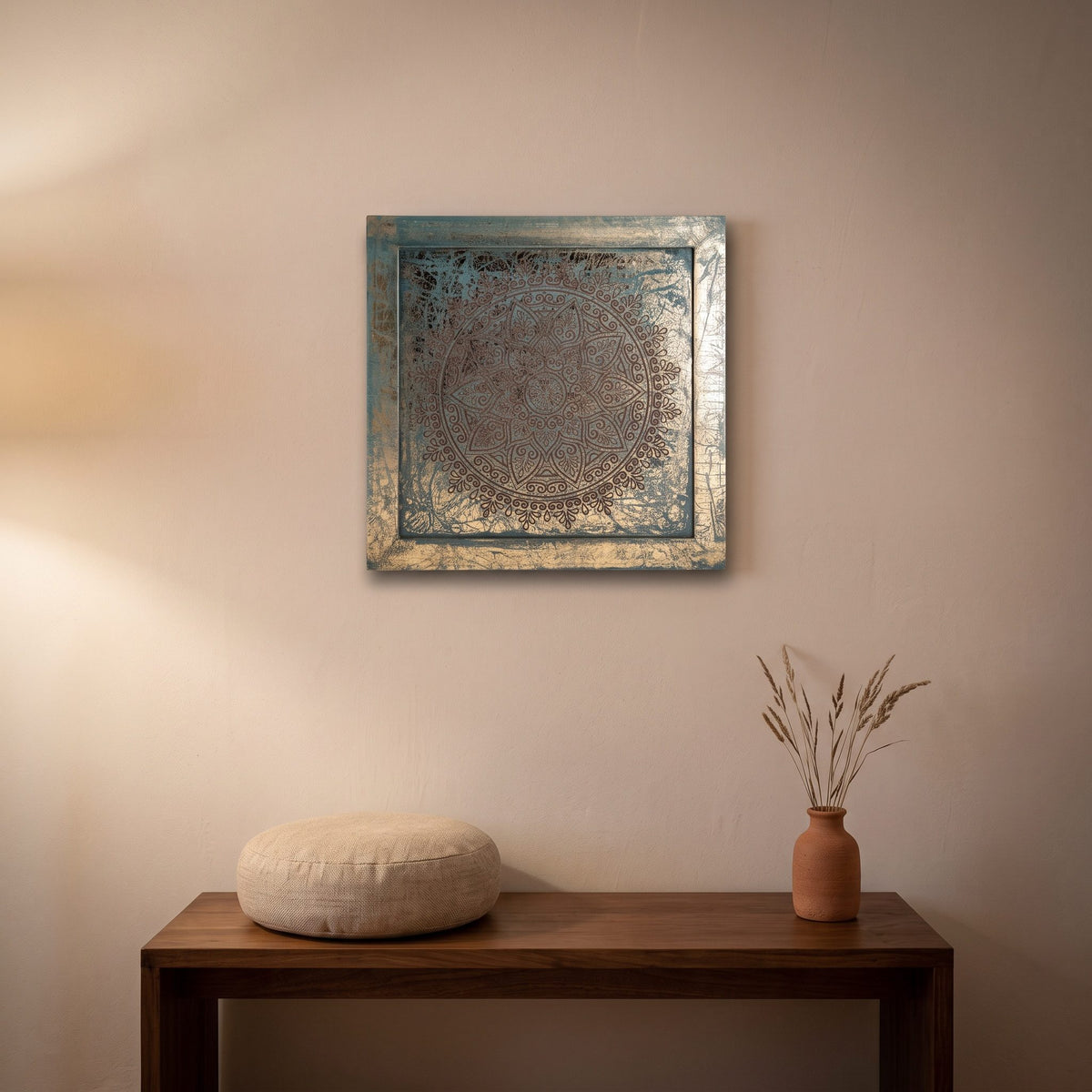 Das Mandala-Wandbild in Grün und Gold über einer Holzbank mit Meditationskissen und einer Vase mit Trockengräsern