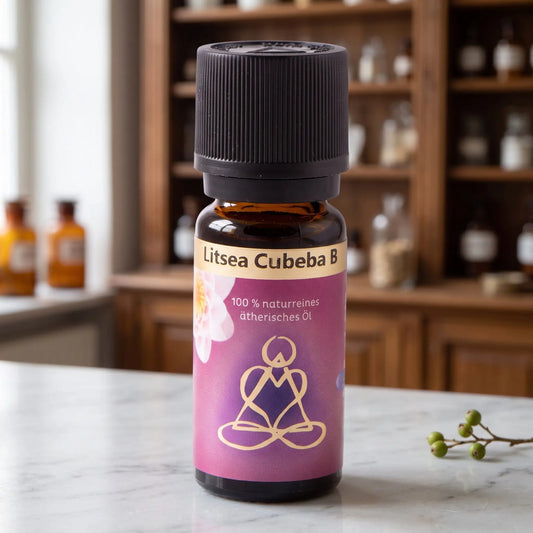 Ätherisches Öl Litsea Cubeba: Fläschchen aus Braunglas auf Marmortheke vor Apothekerschrank, daneben ein Litsea-Zweig mit Beeren – Spirit of Gaia